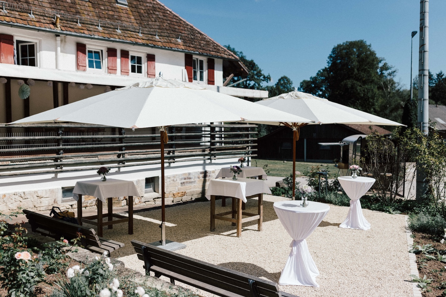 Außenbereich mit Stehtischen und Sonnenschirmen