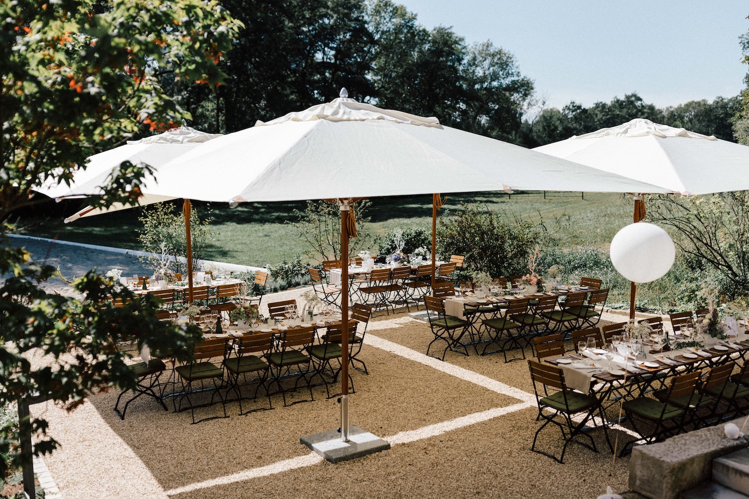 Event-Setup am Fluss mit Holzstühlen und Sonnenschirmen